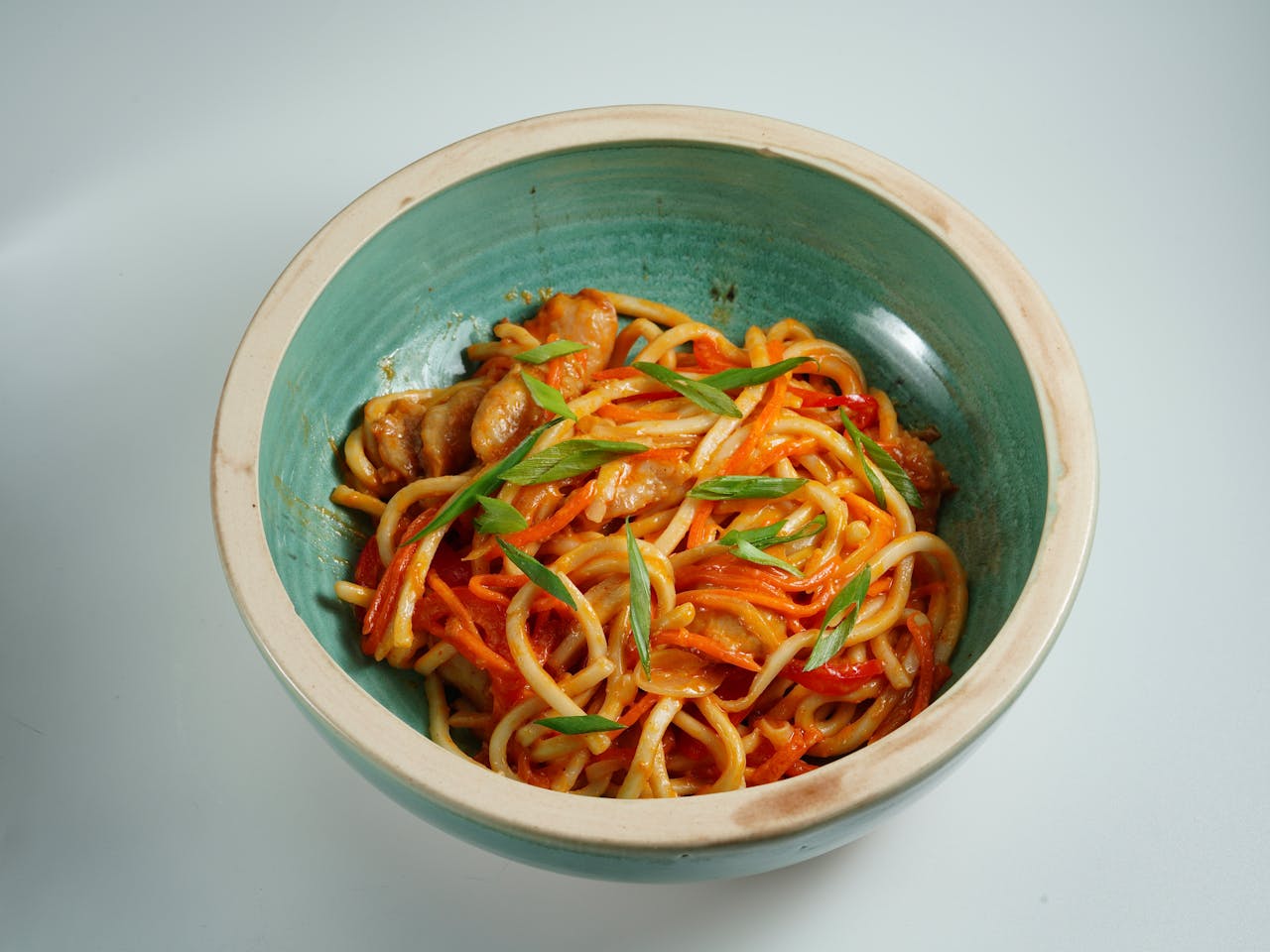 why-choose-us A vibrant bowl of Asian noodles with chicken, vegetables, and garnished with fresh herbs.