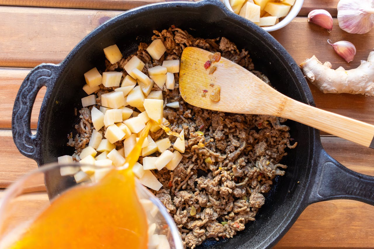 services-04 Ground beef and potatoes cooked in a skillet with broth poured in for a hearty meal.