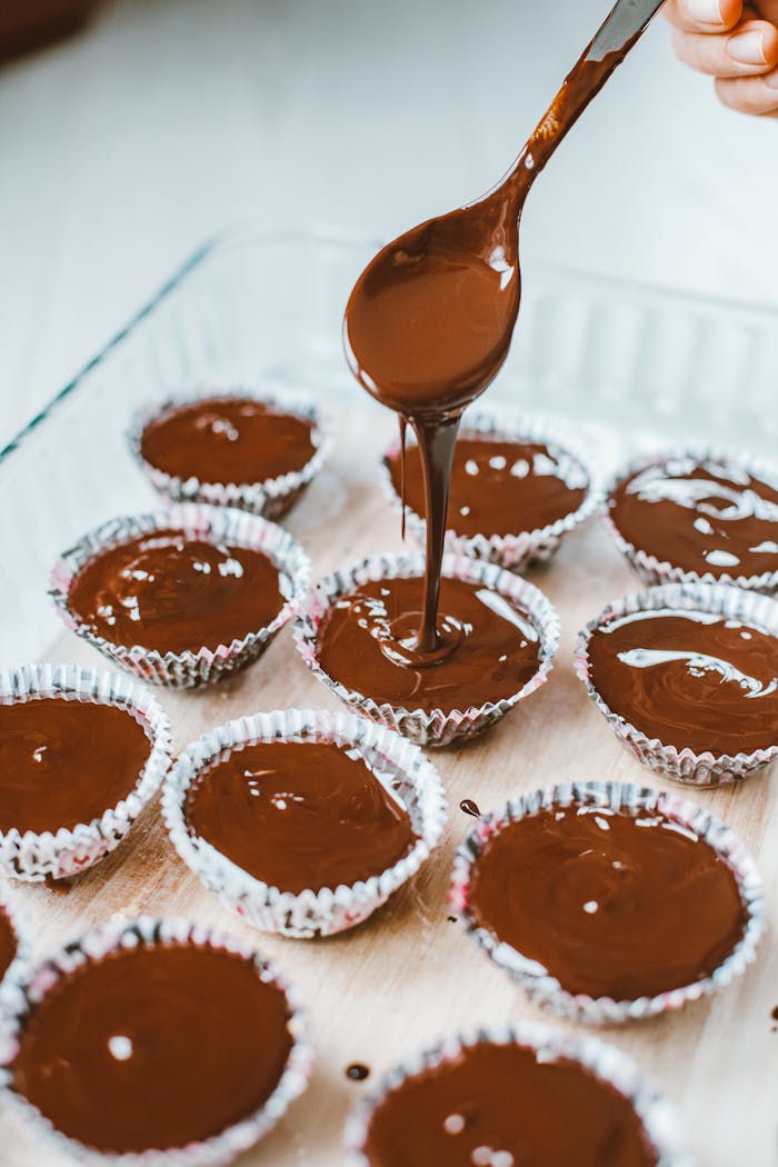 services-03 A person pouring rich chocolate into muffin cups, preparing delicious desserts.