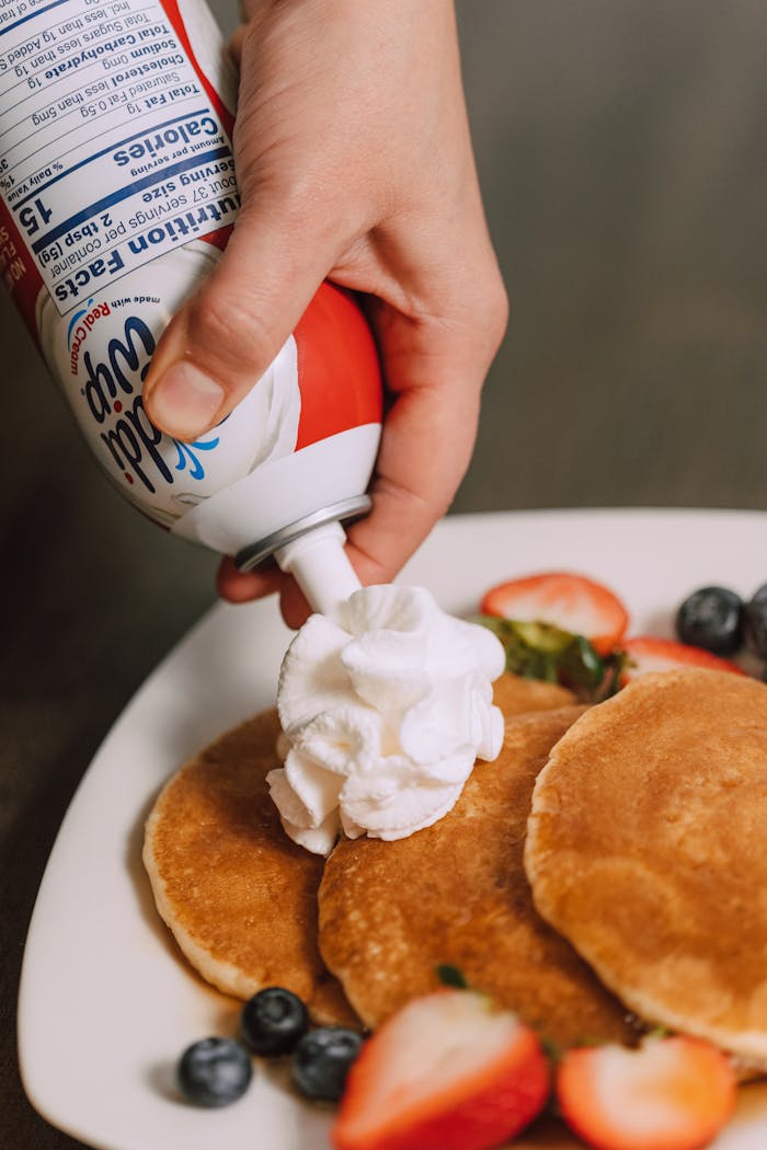 journey Close-up of pancakes topped with whipped cream and fresh berries on a plate. Perfect for breakfast.