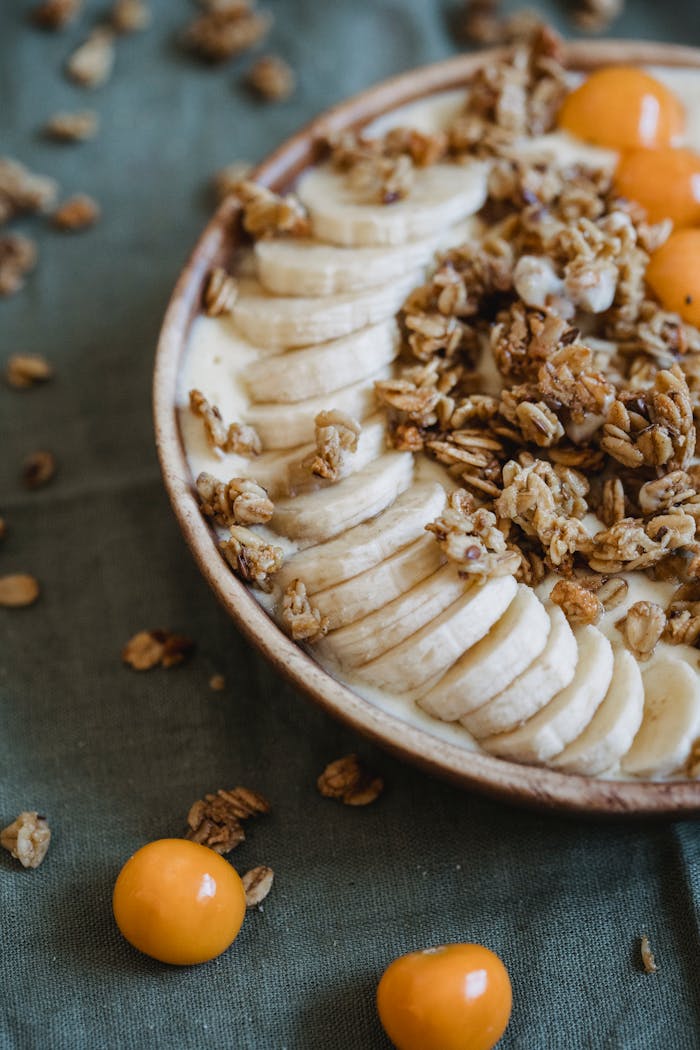 services-02 A nutritious breakfast bowl featuring bananas, granola, and yellow plums, perfect for a healthy start.
