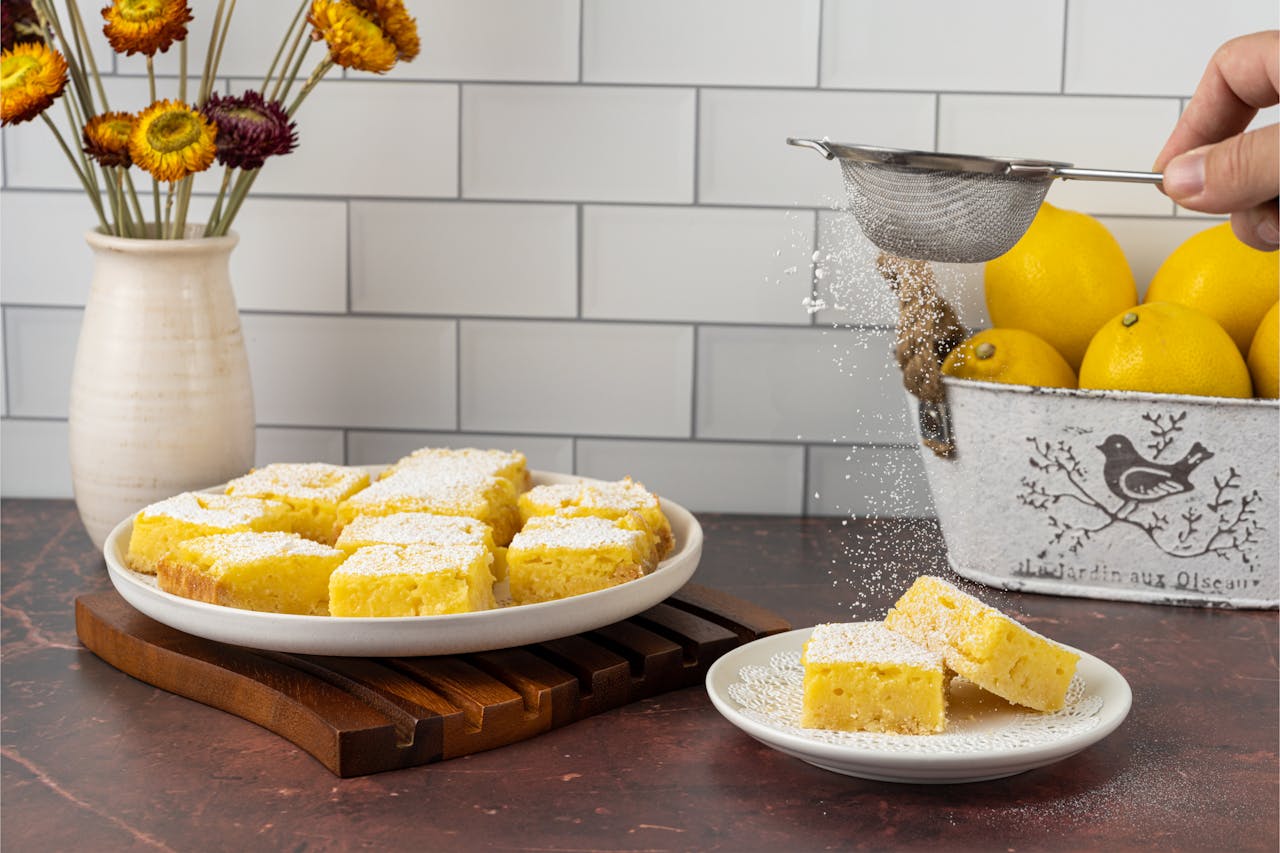 services-01 Freshly baked lemon bars being sprinkled with powdered sugar, perfect for desserts.